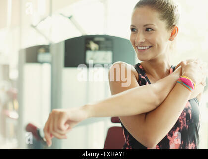 Lächelnde Frau stretching Arm am gym Stockfoto