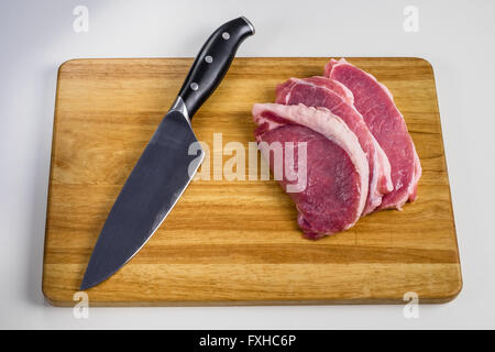 gehackte Stücke vom Schwein auf einem Holzbrett neben das Messer Stockfoto