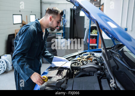 Überprüfen den Ölstand im Motor eines Autos Mechaniker Stockfoto