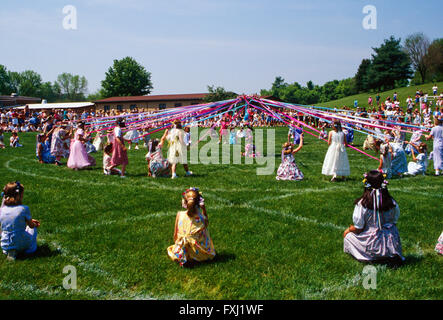 Grundschulkinder tanzen um den Maibaum; Maifeiertag Stockfoto