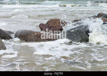 Steinen liegen in einem tobenden Meer unter Schlägen der großen Wellen Stockfoto