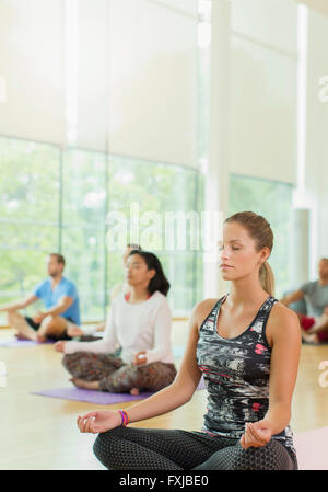 Gelassene Frau im Lotussitz mit geschlossenen Augen in Yoga-Kurs Stockfoto