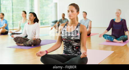 Gelassene Frau im Lotussitz mit geschlossenen Augen in Yoga-Kurs Stockfoto