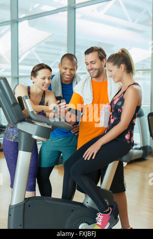 Freunde mit Handy am Heimtrainer im Fitness-Studio Stockfoto