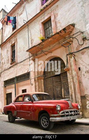 Vertikale Ansicht von einem alten klassischen Auto geparkt vor einem verfallenen Gebäude in Havanna, Kuba. Stockfoto