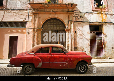 Horizontale Ansicht eines alten klassischen Autos geparkt vor einem verfallenen Gebäude in Havanna, Kuba. Stockfoto