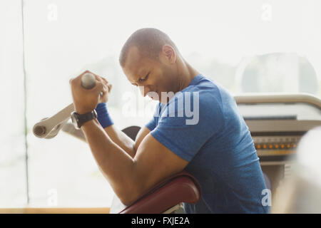 Mann tut Bizeps curls ein Trainingsgeräten im Fitnessstudio Stockfoto