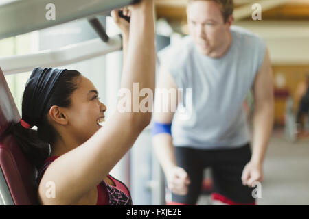 Personaltrainer Führung begeistert Frau mit Trainingsgeräten im Fitnessstudio Stockfoto