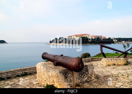 Pula, Istrien, Kroatien. Blick auf Kap Verudela von Pjescana Uvala. Im Vordergrund eine Kanone des Habsburger-Reiches. Stockfoto