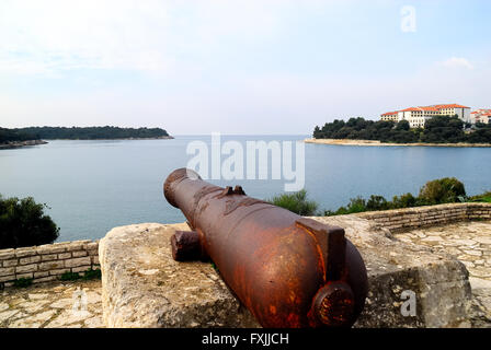 Pula, Istrien, Kroatien. Blick auf Kap Verudela von Pjescana Uvala. Im Vordergrund eine Kanone des Habsburger-Reiches. Stockfoto