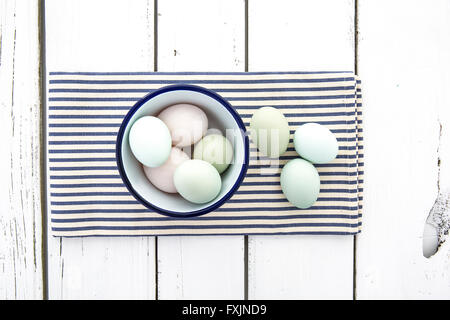 Alten Cotswold erscheinen freien Bereich Eiern mit Pastell farbigen Schalen in einer Schüssel auf einer blau-weiß gestreiften Serviette über rustikalen Tisch Stockfoto