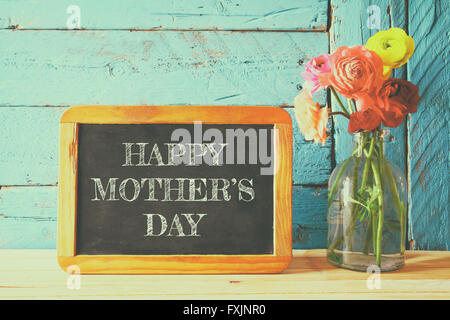 Blumen neben Tafel, auf Holztisch. Muttertag-Konzept Stockfoto