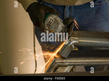 Mann, der arbeitet mit Scheibe Schleifer nach dem Schweißen mit Funken Stockfoto