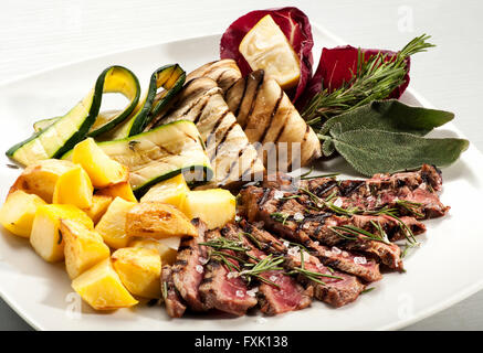 Portion selten gekochtes Steak Scheiben, gelbe Ofenkartoffel, Auberginen und Kürbis mit Kräutern auf Platte Stockfoto