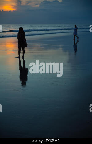 2 silhouettenhafte Figuren am Strand bei Sonnenuntergang in Asien Stockfoto