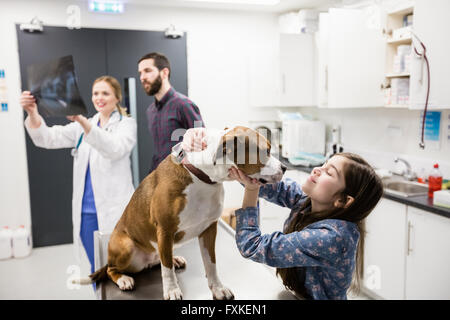 Mädchen spielen mit ihrem Hund beim Tierarzt Röntgen im Hintergrund diskutieren Stockfoto