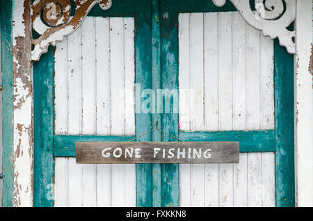 Nahaufnahme eines Zeichens vorbei Angeln eine verwitterte Tür mit gerissenen Malerei in weiß und grün Stockfoto