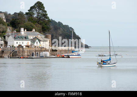 Eine Yacht verlassen den Hafen von Dartmouth Devon UK mit Häusern in Kingswear im Hintergrund Stockfoto