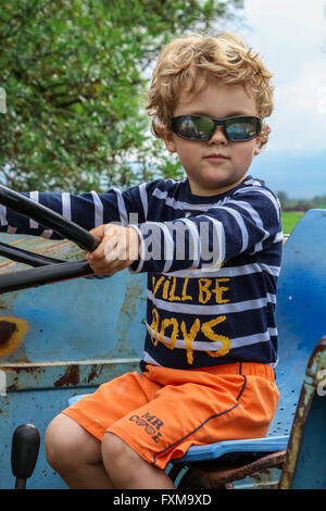 Foto des jungen mit Sonnenbrille auf der alten blauen Traktor Stockfoto