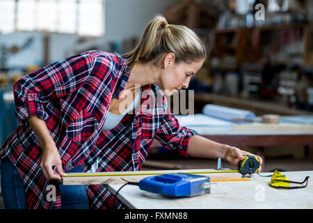 Frau Zimmermann Messlänge von Holzbrett Stockfoto