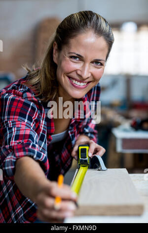 Frau Zimmermann Messlänge von Holzbrett Stockfoto