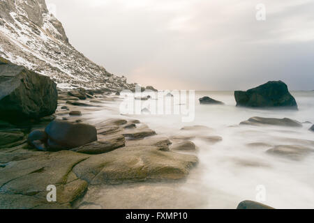 Wellen über Utakleiv Beach, Lofoten Inseln, Norwegen im Winter fließt. Stockfoto