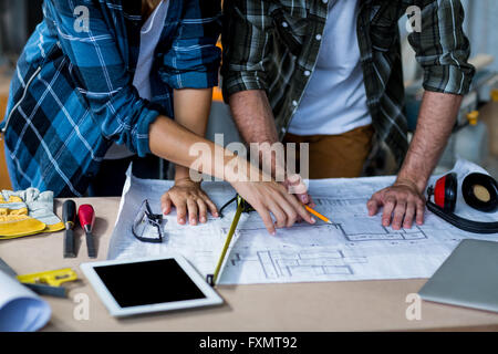 Männliche und weibliche Tischler diskutieren auf Blaupause Stockfoto