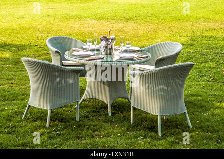 Weiße Rattan-Möbel, Tisch, Stühle und Kissen im Freien im Garten Stockfoto