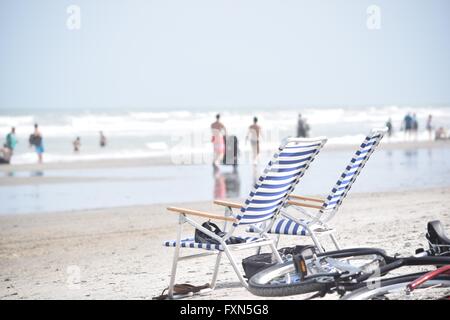 Stühle und Fahrrad am belebten Strand Stockfoto