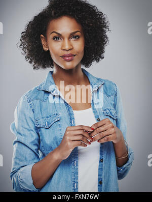 Ruhig Frau mit rotem Nagellack und blaue Jeans Hemd vor grauem Hintergrund Stockfoto