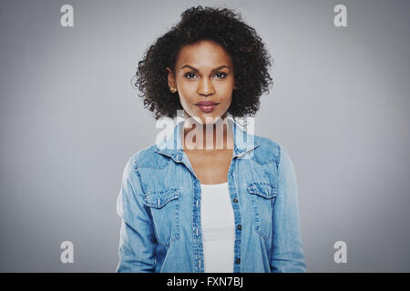 Schwere schöne schwarze Frau mit blauen Jeans Shirt auf grauem Hintergrund Stockfoto
