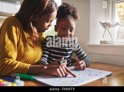 Schwarze Mutter ihre Tochter zu Hause das Alphabet lernen verwenden Farben zum Zeichnen Stockfoto