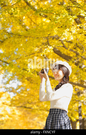 Junge Japanerin mit Vintage-Kamera in einem Stadtpark Stockfoto