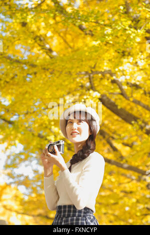 Junge Japanerin mit Vintage-Kamera in einem Stadtpark Stockfoto