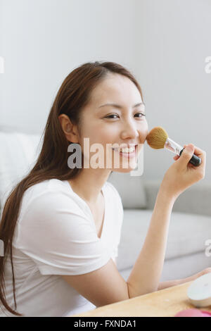 Junge attraktive Japanerin tun ihr Make-up zu Hause Stockfoto