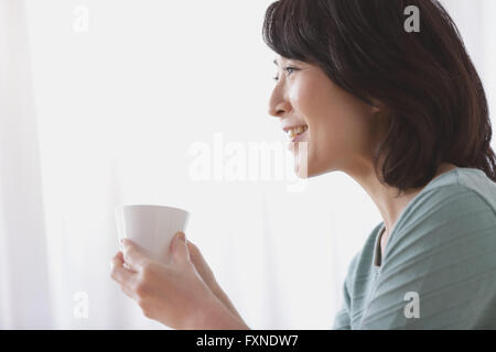 Ältere Japanerin Kaffeetrinken im Wohnzimmer Stockfoto