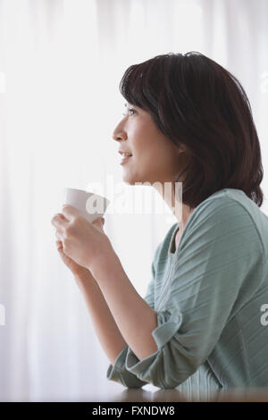 Ältere Japanerin Kaffeetrinken im Wohnzimmer Stockfoto