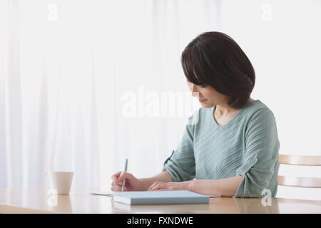Ältere Japanerin Buchhaltung im Wohnzimmer zu tun Stockfoto