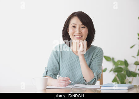 Ältere Japanerin Buchhaltung im Wohnzimmer zu tun Stockfoto