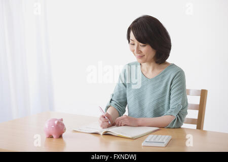 Ältere Japanerin Buchhaltung im Wohnzimmer zu tun Stockfoto