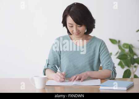 Ältere Japanerin Buchhaltung im Wohnzimmer zu tun Stockfoto