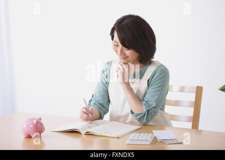 Ältere Japanerin Buchhaltung im Wohnzimmer zu tun Stockfoto