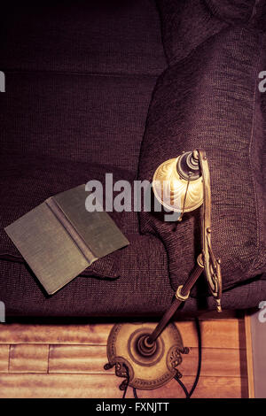 Vintage Buches offen auf dem Arm eine Couch mit einer Leselampe erschossen von oben. Stockfoto