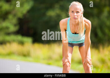 Schlanke junge Frau Fang ihr Atem nach einem langen Lauf Stockfoto