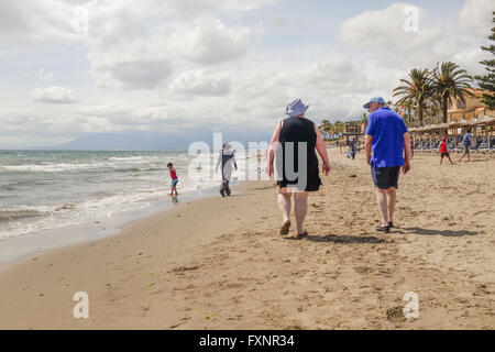 Älteres Ehepaar bei einem Spaziergang entlang des Strandes in Spanien, bei bewölktem Wetter. Andalusien, Spanien. Stockfoto