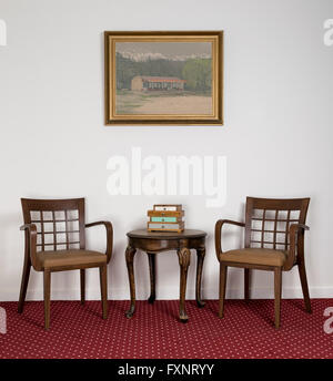 Sessel aus Holz, kleine Runde Couchtisch und gerahmte Gemälde Stockfoto