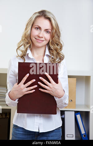 Glücklich blonde Frau mit Anwendungsportfolio im Büro Stockfoto