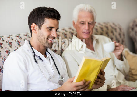 Krankenschwester und Senior Mann liest ein Buch Stockfoto