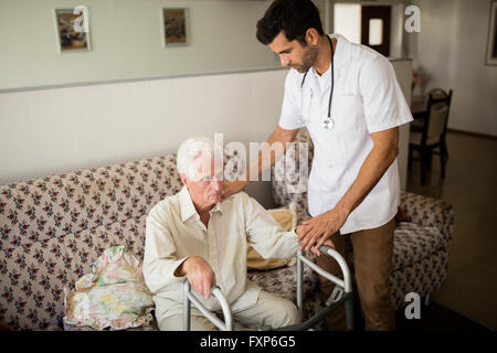 Krankenschwester, die ältere Menschen aufstehen helfen Stockfoto