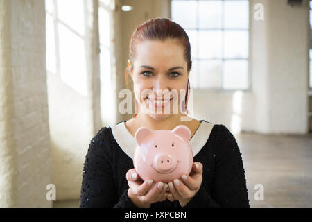 Glückliche Frau hält ein Sparschwein lächelnd Stockfoto